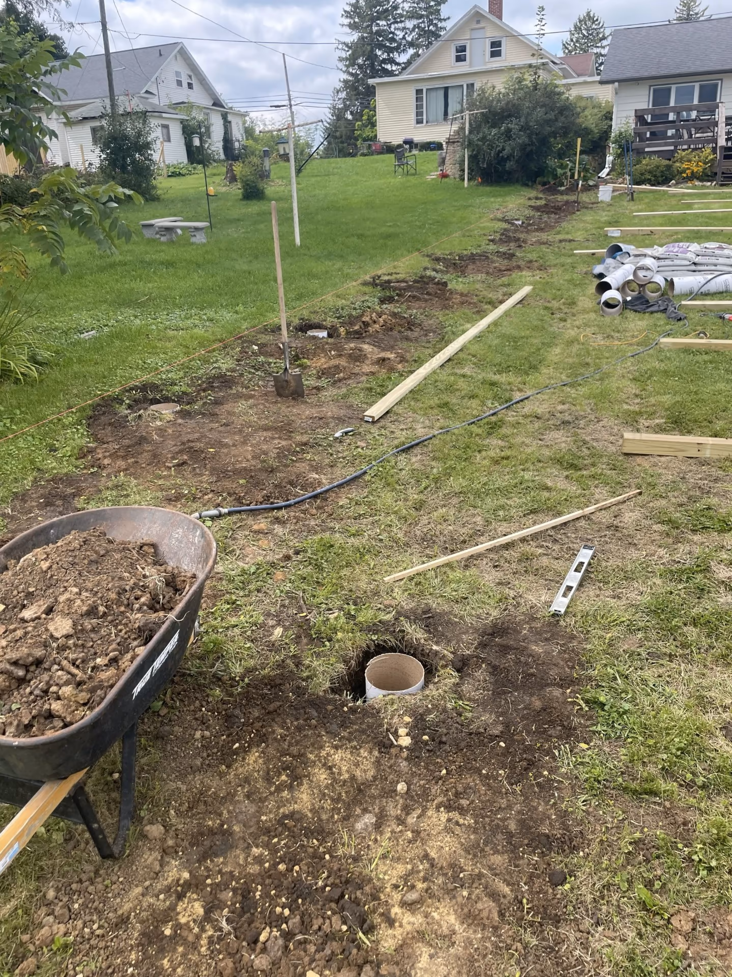 Fence post preparation with wheelbarrow and layout strings